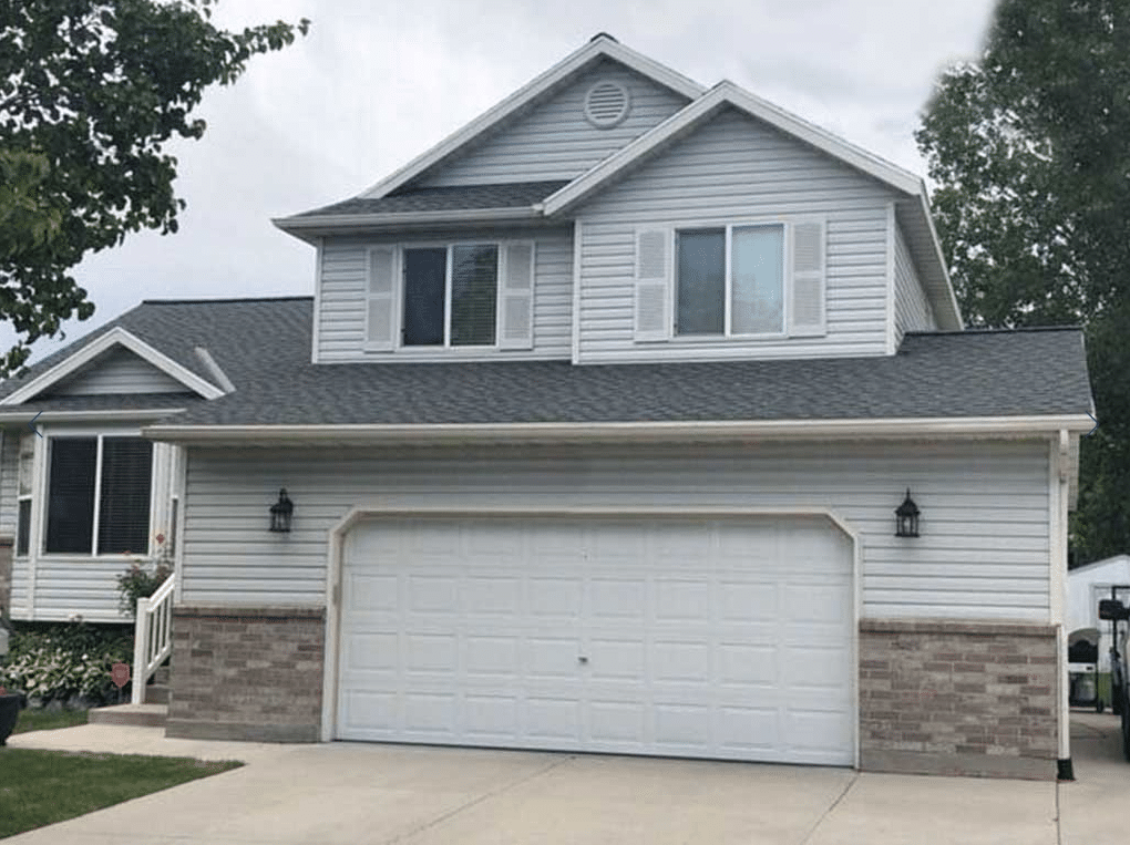 Suburban two-story house with a large front-facing garage under an overcast sky.
